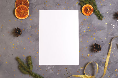 Christmas composition. A piece of paper with brunches, oranges, cones and ribbons on gray marble background. Copy space, top view. Merry christmas greeting card. Flat layの写真素材