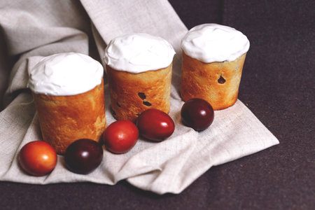 Easter pastries and colored eggs on a textile background. Spring composition. Traditional pastries...