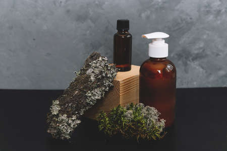 Spa cosmetics in brown glass bottles on natural background of moss, wood, tree bark and fern. Copy space for text. Beauty blogger, salon therapy, branding mockup, minimalism concept.の写真素材