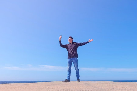 Young man tourist traveller blogger talking video chat walking at sea pier, low angle view. Guy...
