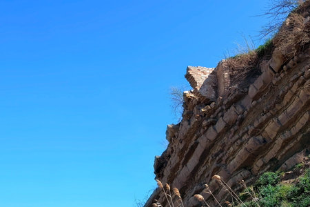 Ruins of brick house on top of broken rock mountain after earthquake tsunami nature disaster on blue...