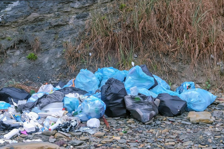 Dump garbage bags in nature near mountains. Environmental pollution outdoors and ecological...