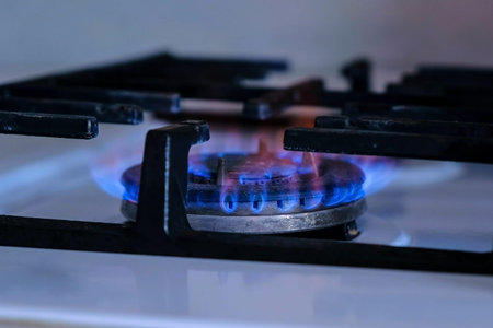 Natural gas inflammation in stove burner. Gas burning from a kitchen gas stove. Close-up side view...