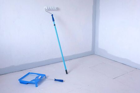 Two paint rollers and paint pan with grey paint in room near wall, painting works. Renovation and construction works at room in flat, apartment, house. Prepared tools for work. Final finishing job.の写真素材