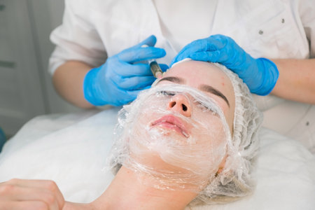 PRP therapy in beauty clinic. Cosmetologist doing injections of blood plasma to woman's forehead to cure problem skin, closeup top view. Treatment of skin in cosmetology for young female.の写真素材
