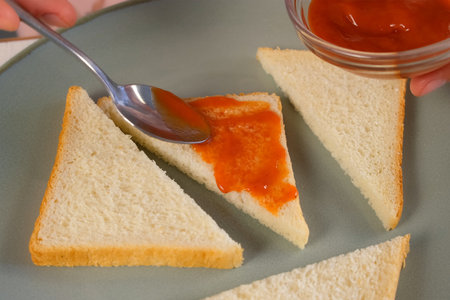 Woman smearing toasts bread with tomato sauce cooking hot sandwiches on kitchen at home. Preparing snack fast food for herself. Tasty fresh meal for fast eating.の写真素材