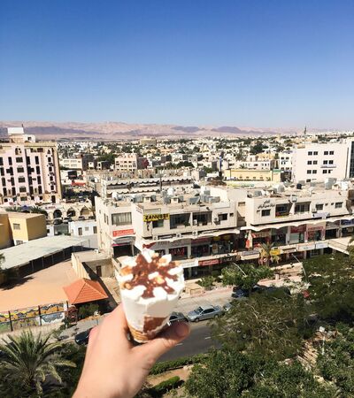 View overlooking the town. In the girlâs hand, ice cream on the background of the Arab city. Jordan, Akaba.のeditorial素材