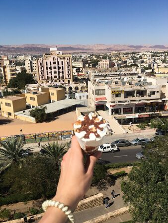 View overlooking the town. In the girlâs hand, ice cream on the background of the Arab city. Jordan, Akaba.のeditorial素材