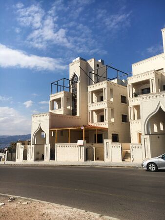 A beautiful white building opposite the road behind the mountain in front of the building is a car. Jordan, Aqaba.のeditorial素材