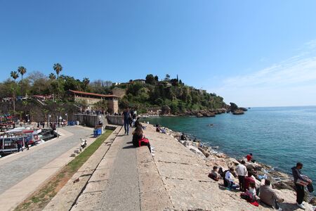 People sits along the coast and look at the Mediterranean sea. Tourist port. Turkey, Antalya.のeditorial素材