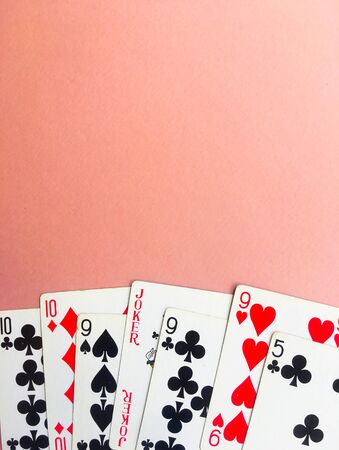 Cards for playing poker lie at the bottom of a pink background. Place for text. Gambling.のeditorial素材