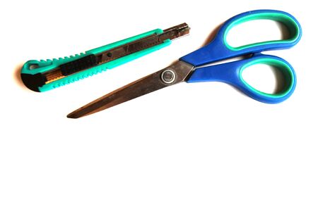 Blue scissors and a green stationery knife on a white isolated background. Copy space. View from above.の写真素材