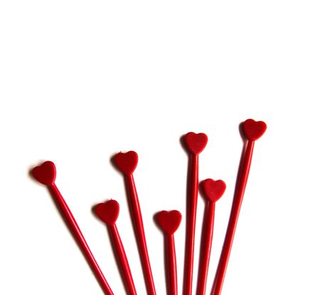 Red plastic sticks for canapes with a heart on a white isolated background. Decorative chopsticks.の写真素材