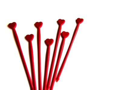 Red plastic sticks for canapes with a heart on a white isolated background. Decorative chopsticks.の写真素材