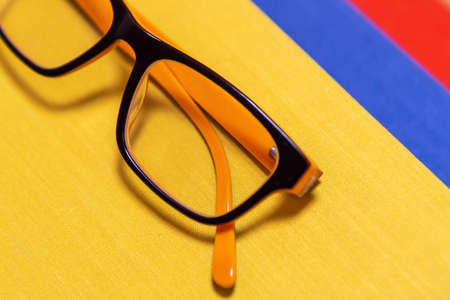 Glasses on a stack of books on a yellow background. The concept of the habit of reading or studying. Knowledge from books. Scientific background.の写真素材