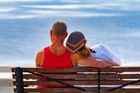 A man and a woman in love are sitting on a bench by the sea and hugging.の写真素材