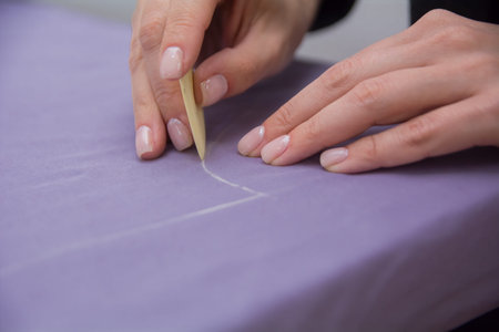 The seamstress traces the pattern with chalk on the fabric.