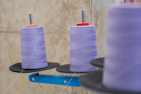 Bobbins of purple thread on a sewing machine.