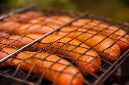 Sausages that are fried in a metal grate on a fireの写真素材