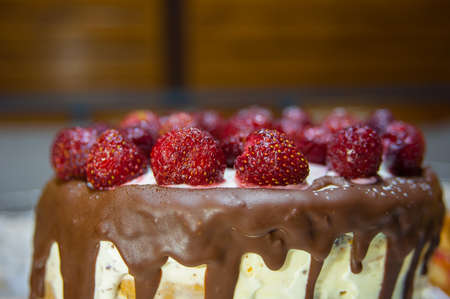 Homemade and handmade cake topped with chocolate and countryside strawberriesの写真素材