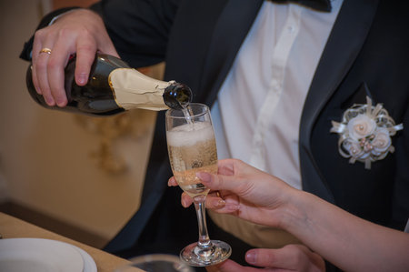 Young people pour champagne to each other at a gala eveningの写真素材