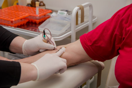 The doctor draws blood from a vein from the patient using a system for analysis.の写真素材