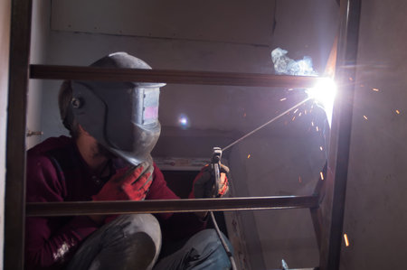 Welder during work process, joining two elements