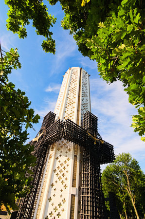 Kyiv, Ukraine-July 03, 2022: Memory candle is the central part of Monument to Victims of Famine devoted to genocide victims of the Ukrainian people of 1932-1933. Tree leaves boarder. Wide-angle view.のeditorial素材