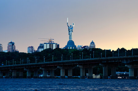 Kyiv, Ukraine-July 17,2022: Famous Motherland Monument (Rodina mother) on stormy sky and gloomy clouds background. Unfinished multi-story apartment buildings in the background.のeditorial素材