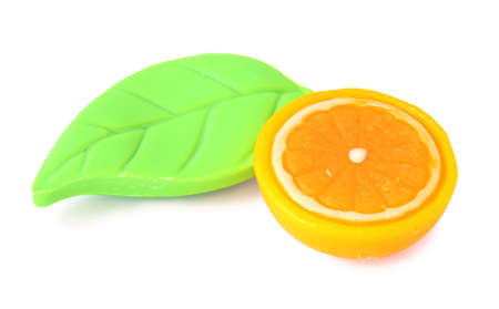 Two pieces of soap in the form of cut orange and green leaf. It is isolated on white background.の写真素材