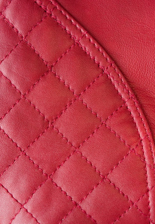 Red leather background with rhombus, seams and smooth surface in corner.