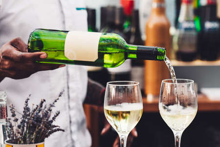 The waiter pours wine into a glass. Barの写真素材