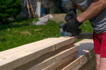 man planning boards with electric tools, chips flying in all directions. Construction, wood processingの写真素材