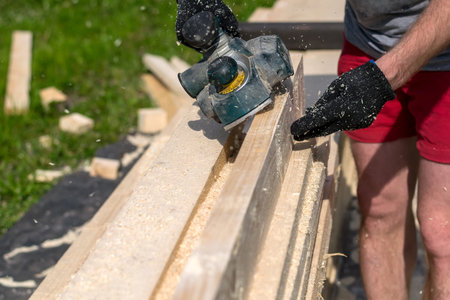 man planning boards with electric tools, chips flying in all directions. Construction, wood...