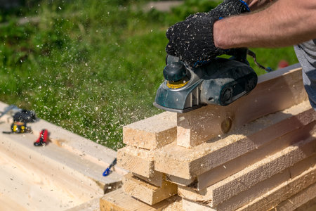 man planning boards with electric tools, chips flying in all directions. Construction, wood...