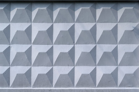 Background, wall of large gray blocks with triangular patterns and sun shadowsの写真素材