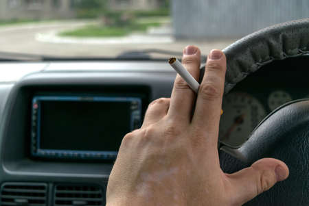 close-up, the hand of the driver of the car with skin disease "vitiligo" holds a cigaretteの写真素材