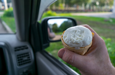 the driver holds the ice cream while driving a car
