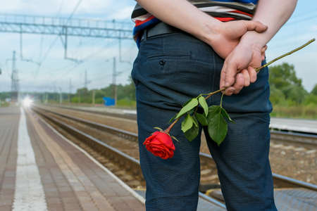 view of a man with a rose flower at the railway stationの写真素材