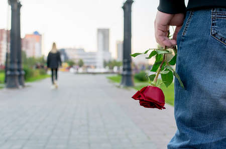 red rose flower in the hand of the guy on the background of the girlの写真素材