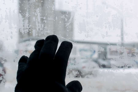 human hand on the icy glass of the car with snow patternsの写真素材