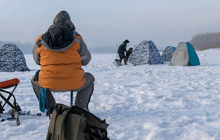 the fisherman on winter fishing on ice of the lakeの写真素材