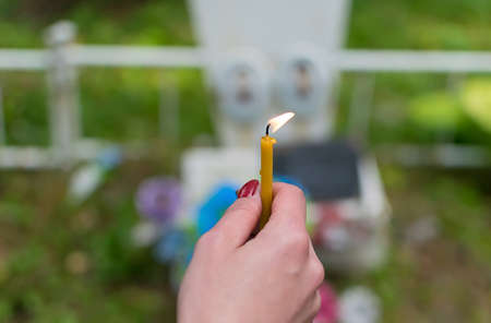 The flame of a wax candle in the hand of a people in the cemeteryの写真素材