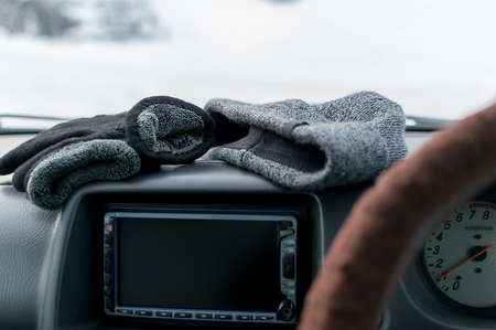 close up, warm winter gloves and a hat lie on the car panelの写真素材