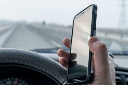 in the hand of the driver of the car, a cell mobile phone