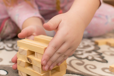 hands of a little girl, a child who plays sitting on the floor of the houseの写真素材