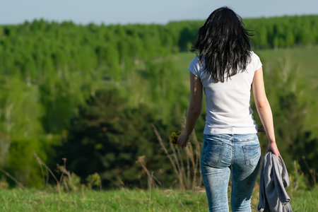 a slender beautiful girl with dandelions in her hand