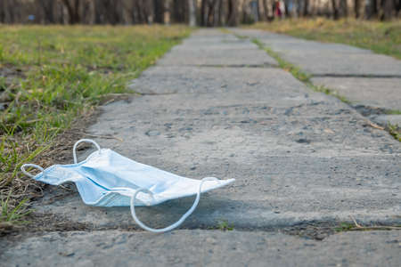 a medical mask lies on a footpathの写真素材