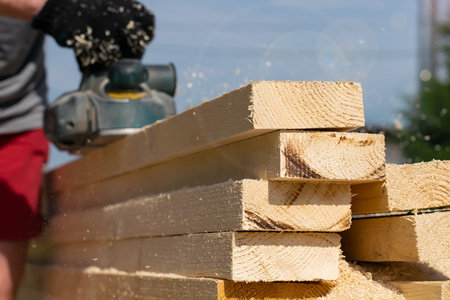 long wooden bars, boards that a worker handles with a power tool