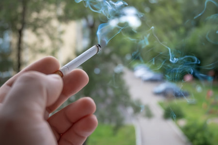 View of the hand of a Smoking man with a Smoking cigarette from the window of the apartment into the...